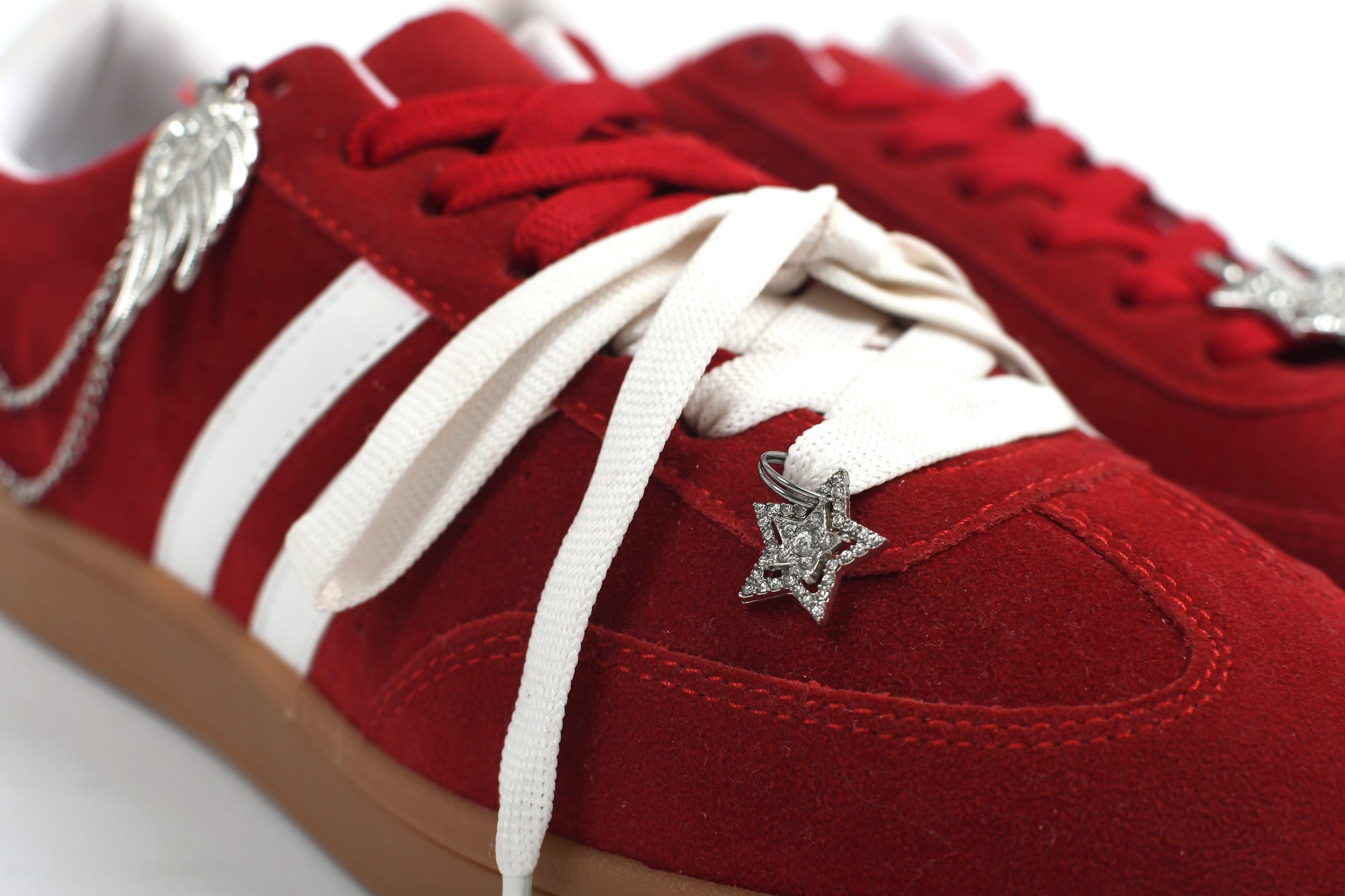 Red sneakers with white laces and decorative elements on a white background