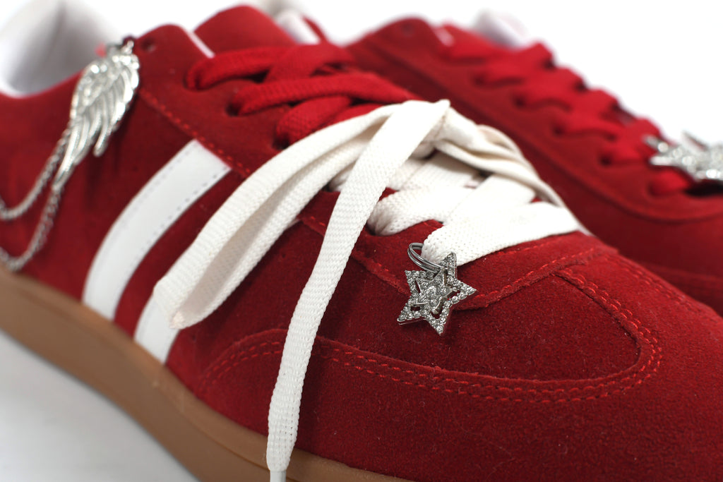 Red sneakers with white laces and decorative elements on a white background