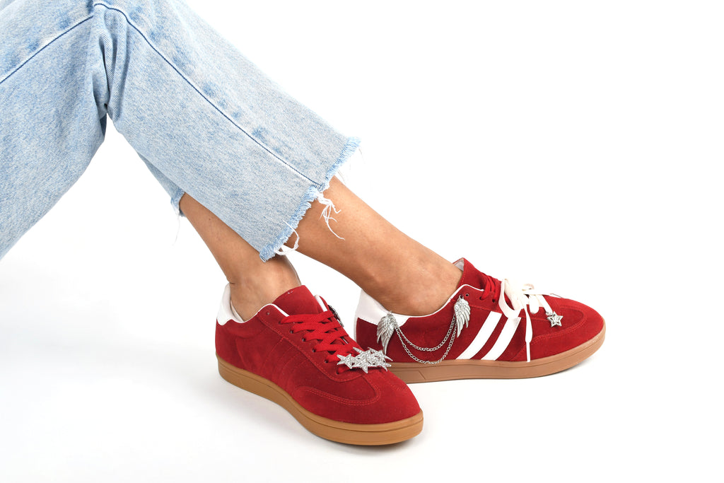 Red sneakers with white accents worn with light blue jeans on a white background