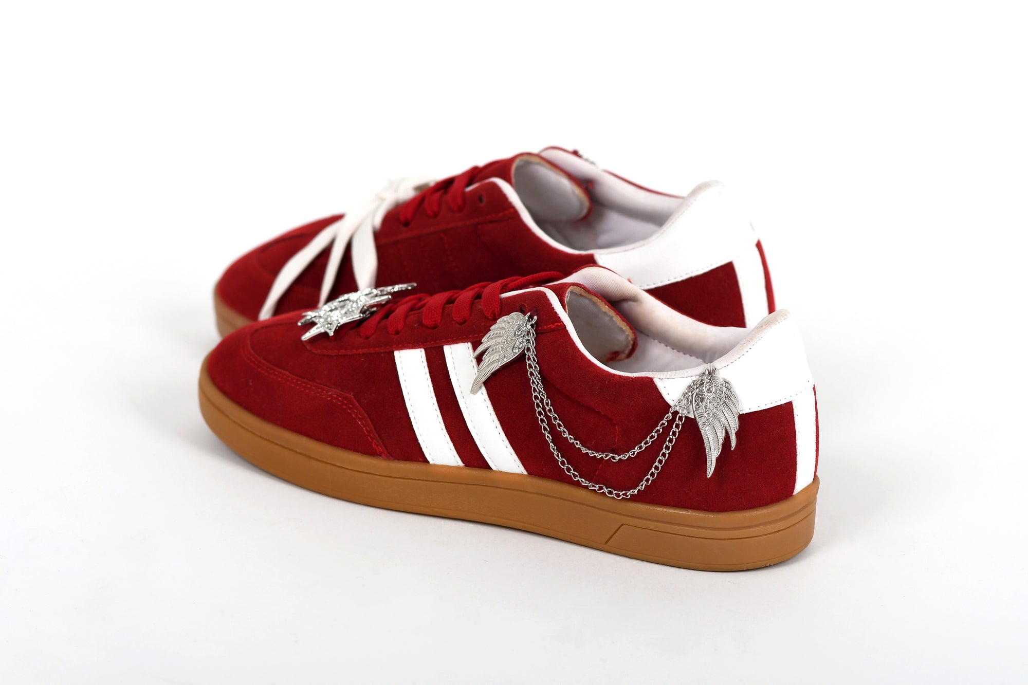 Red sneakers with white stripes and gold soles on a white background